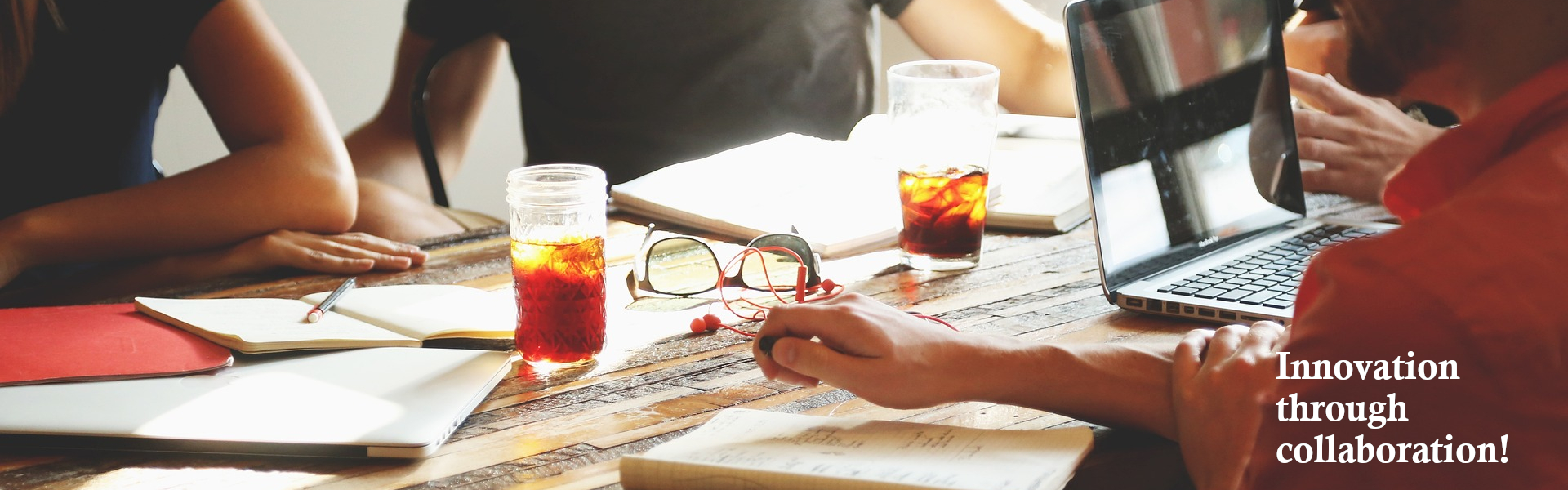 Picture of meeting rouns a table with a caption of: Innovation through collaboration